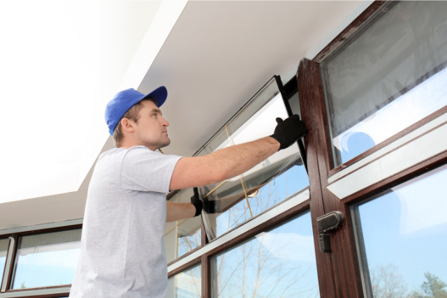 Worker Repairing Window in House